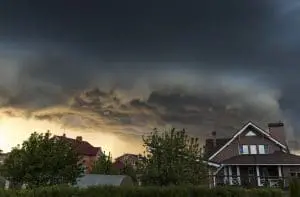 A dark sky with clouds and sun behind it